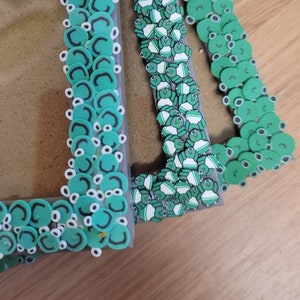 May include: Three picture frames decorated with green and white frog designs. The frames are made of wood and have a clear plastic front.