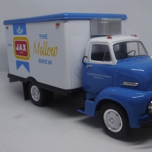 Könnte beinhalten: Ein blauer und weißer Spielzeug-Lieferwagen mit den Worten "The Mellow Brew" und "Jax" an der Seite. Der LKW ist ein Modell eines Ford aus den 1950er Jahren.