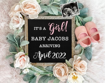 Puede incluir: Un tablero de letras negro con el texto "It's a girl! Baby Jacobs Arriving April 2022". El tablero está rodeado de flores rosas y vegetación. Hay una imagen de ultrasonido en blanco y negro en la esquina superior derecha de la imagen.