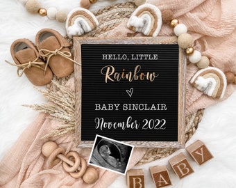 May include: A baby announcement with a black letter board that reads "HELLO, LITTLE Rainbow BABY SINCLAIR November 2022". The image includes baby shoes, wooden blocks spelling "BABY", and a sonogram.