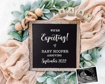 May include: A wooden letter board with the text "We're Expecting! Baby Hooper Arriving September 2022" surrounded by greenery, a wooden baby rattle, and a small ultrasound image.