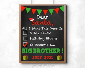 May include: A chalkboard sign with a red and green Christmas theme. The sign says "Dear Santa, All I Want This Year Is: A Toy Truck, Building Blocks, To Become a... BIG BROTHER! JULY 2021".