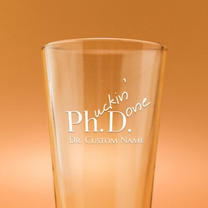 May include: A clear glass pint glass with the text "Ph.D.  F*ckin' Done" and "Dr. Custom Name" etched on the side.