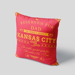 Pode incluir: Travesseiro vermelho com texto dourado que diz "Reservado para pai O maior fã de Kansas City O maior fã de esportes do mundo. O pai número 1 do mundo."