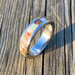 May include: A silver ring with a band of colorful opal-like stones set into the metal.