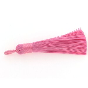 Op de afbeelding: Een roze kwast met een lus om aan een project te bevestigen. De kwast is gemaakt van zachte, zijdeachtige vezels.