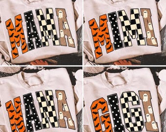 May include: A beige crewneck sweatshirt featuring a large graphic with the text MAMA, MIMI, NANA, or GIGI. Each letter has a unique pattern: orange with black bats, black with white polka dots, a black and white checkerboard, or tan with ghosts.