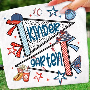 May include: A white fabric surface featuring a graphic design with two pennants labeled Kinder and Garten in blue script. The print includes baseball-themed elements like a baseball, a cap, a glove, cleats, a hot dog, and a drink, accented with red and blue stars.