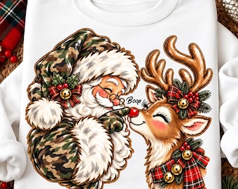 May include: A white sweatshirt featuring a graphic of Santa Claus in a camouflage hat and coat touching the red nose of a reindeer. The reindeer wears a red and green plaid scarf with gold bells. The word Boop is printed between them.