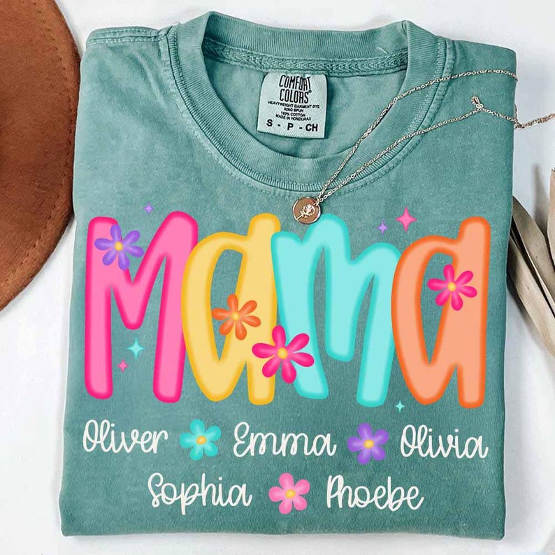 Peut inclure: Un t-shirt vert sarcelle avec le mot "Mama" en lettres color&eacute;es avec des fleurs. Les noms Oliver, Emma, Olivia, Sophia et Phoebe sont &eacute;crits sous le mot "Mama" avec des fleurs entre chaque nom.