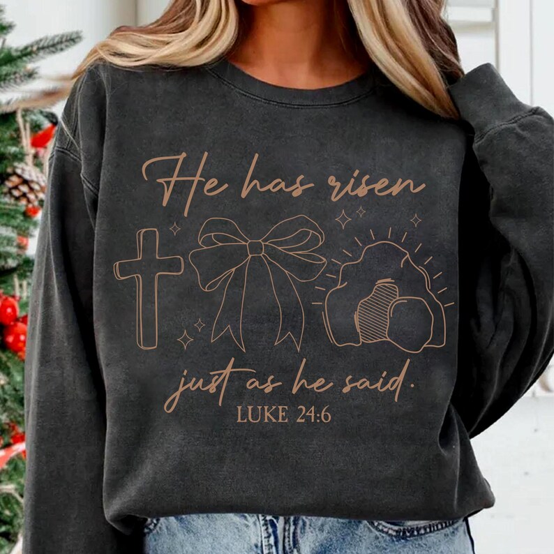 May include: A black sweatshirt with a brown graphic design that says "He has risen just as he said. LUKE 24:6". The graphic includes a cross, a bow, and a tomb.