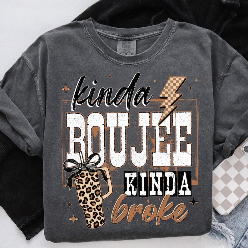 May include: Dark gray sweatshirt with the text "kinda BOUJEE kinda broke" in white and brown lettering. A leopard print tumbler with a black bow is featured on the left. A brown and tan checkered lightning bolt is on the right.