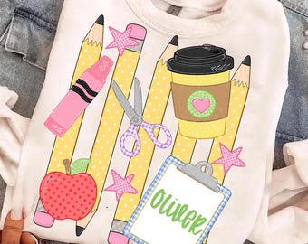 May include: A white sweatshirt featuring a graphic print of yellow pencils with white polka dots, a pink crayon, purple scissors, a red apple, a yellow coffee cup with a pink heart, pink stars, and a blue checkered clipboard with the name Oliver.