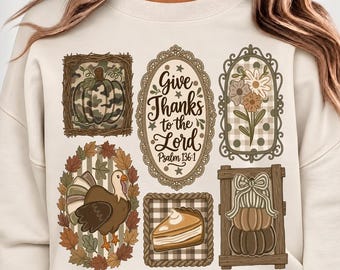 May include: A cream-colored crewneck sweatshirt featuring a graphic print of six framed illustrations: a camouflage pumpkin, a floral arrangement, a turkey, a slice of pie, stacked pumpkins with a bow, and text reading Give Thanks to the Lord Psalm 136:1.