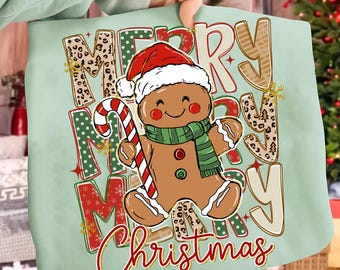 May include: A light green tote bag featuring a gingerbread man wearing a Santa hat and scarf, holding a candy cane. The words "Merry Christmas" are printed in a festive design with leopard print accents.