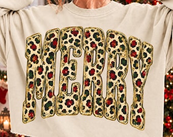 May include: A beige long-sleeve sweatshirt featuring the word MERRY in large, bold, block letters. The letters have a gold outline and are filled with a repeating leopard print pattern containing red and dark green circular spots.