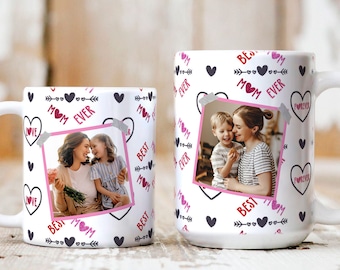 Puede incluir: Dos tazas de cerámica blanca con un diseño en negro y rosa. Las tazas presentan una foto de una madre y un hijo, corazones, flechas y el texto "Best Mom Ever".