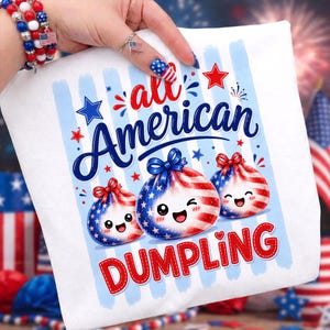 Op de afbeelding: Wit T-shirt met een patriottisch ontwerp met drie lachende dumplings versierd met rode, witte en blauwe sterren en strepen. De tekst "all American DUMPLING" staat speels boven en onder de dumplings.