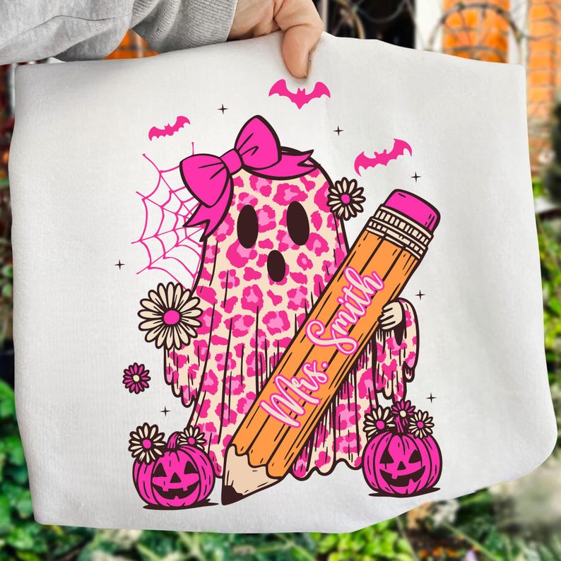 May include: White Halloween-themed design featuring a pink leopard print ghost wearing a bow, holding a pencil with "Mrs. Smith" written on it. Includes pink pumpkins, bats, spiderweb, and flowers. A fun, festive design.