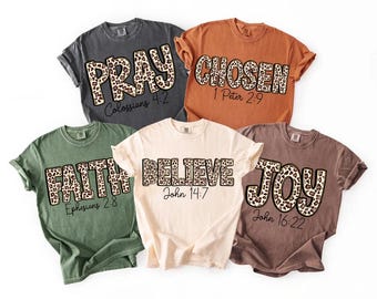 May include: Five t-shirts in various colors, each with a different word in a leopard print font: PRAY, CHOSEN, FAITH, BELIEVE, and JOY. Each shirt also has a corresponding Bible verse printed below the word.