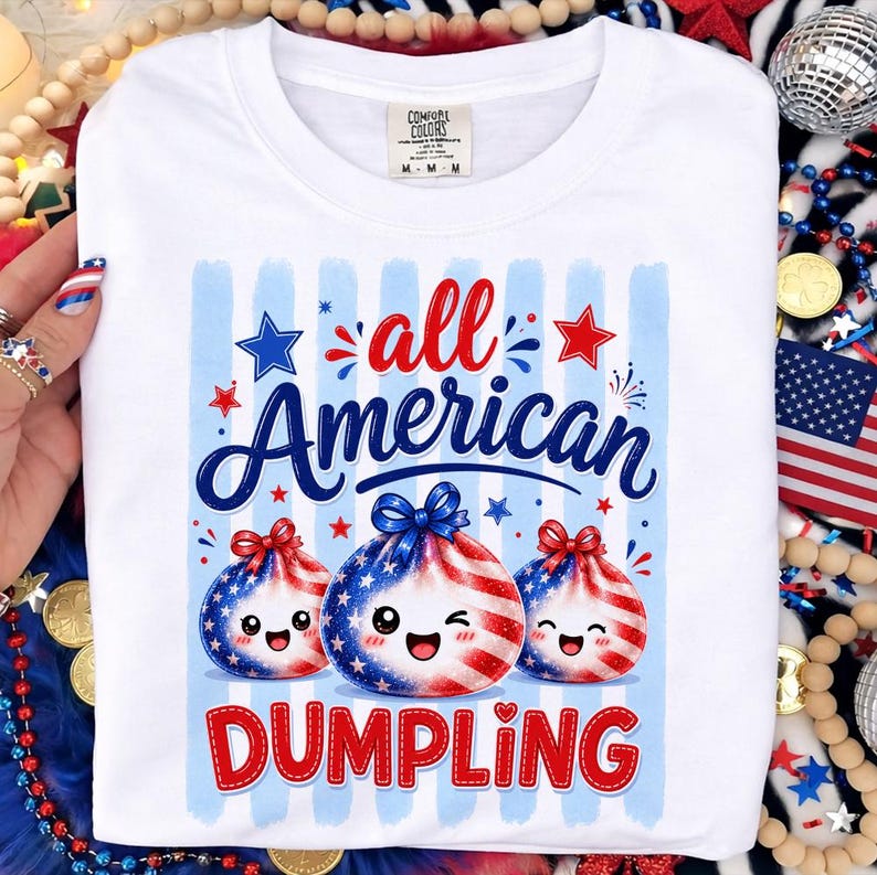 Op de afbeelding: Witte sweatshirt met een afbeelding met de tekst "all American DUMPLING" in rood en blauw. Het ontwerp bevat drie dumpling-personages met patriottische rood-wit-blauwe patronen en lachende gezichten. De trui heeft een ronde hals.
