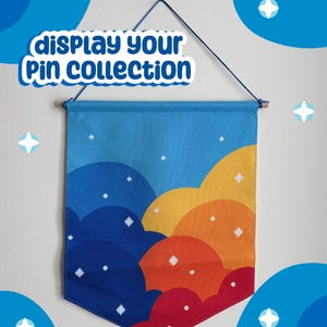 May include: A rectangular fabric wall banner featuring a gradient of overlapping clouds in shades of blue, yellow, orange, and red, accented with white four-pointed stars. The banner includes the text display your Pin collection in blue letters.