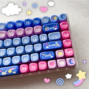 Puede incluir: Un teclado blanco con teclas de color azul pastel, rosa y morado. Las teclas tienen varios símbolos y diseños, incluyendo estrellas, nubes, arcoíris y corazones. El teclado tiene una fila de teclas de función, una fila de números, una fila de letras y una fila inferior con teclas como 'Alt', 'Fn' y 'Ctrl'.