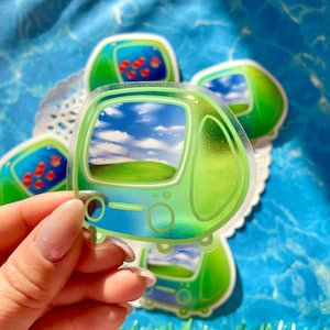 May include: Several clear stickers with a green and blue design, resembling a retro television. The screen shows a landscape of a blue sky with clouds and a green hill. Other stickers show red fish in a blue tank.