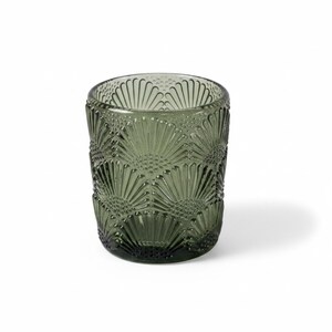 K&ouml;nnte beinhalten: Ein dunkelolivgr&uuml;ner Glastrinkbecher mit einem sich wiederholenden, gepr&auml;gten F&auml;cher- oder Muschelmuster auf der Au&szlig;enfl&auml;che. Das Gef&auml;&szlig; hat eine zylindrische Form mit einem glatten Rand und einer strukturierten, durchscheinenden Oberfl&auml;che.