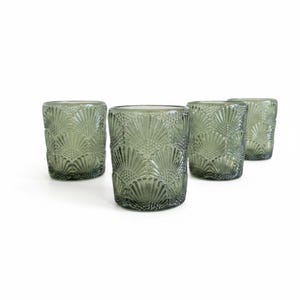 K&ouml;nnte beinhalten: Ein Set aus vier zylindrischen Trinkgl&auml;sern in einem ged&auml;mpften Salbeigr&uuml;n. Jedes Glas weist ein sich wiederholendes, gepr&auml;gtes f&auml;cherf&ouml;rmiges Muster auf, das die Au&szlig;enfl&auml;che bedeckt und eine texturierte Optik mit halbtransparenter Oberfl&auml;che erzeugt.