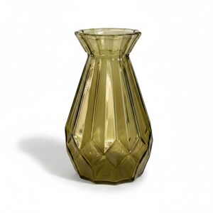 May include: A translucent olive green glass vase featuring a wide, flared rim and a geometric, faceted body with vertical panels that taper toward the base. The vessel has a smooth, polished finish and a distinct, multi-sided structure.