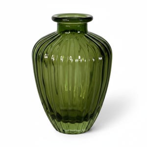 May include: A translucent olive green glass vase featuring a rounded body with vertical ribbed detailing. The vessel has a wide, short neck with a thick, rounded rim at the top, creating a distinct silhouette with light reflecting off the glass.