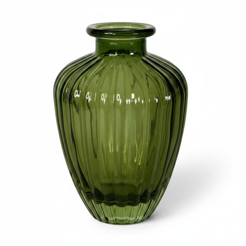 May include: A translucent olive green glass vase featuring a rounded body with vertical ribbed detailing. The vessel has a wide, short neck with a thick, rounded rim at the top, creating a distinct silhouette with light reflecting off the glass.