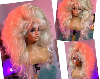 May include: A large, blonde wig with a high bouffant and long, wavy curls. The wig is styled in a 1960s beehive style.