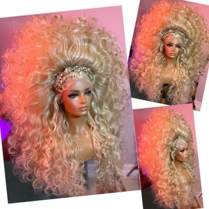 May include: A large, blonde wig with long, curly hair. The wig is styled in a high, voluminous bouffant with a braided headband.