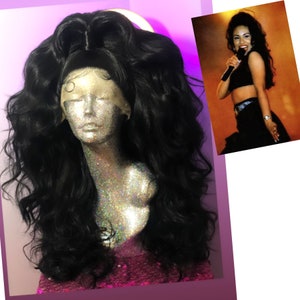 May include: A black wig with long, loose curls styled in a high ponytail. The wig is on a mannequin head with a glittery surface.