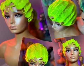 Puede incluir: Una peluca de color verde neón con un estilo corto y rizado. La peluca está diseñada con un estilo vintage, pin-up con raya lateral y flequillo rizado.