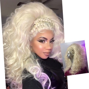 May include: A blonde wig with a braided crown, styled in large, loose curls. The wig is on a mannequin head and has a natural, voluminous look.