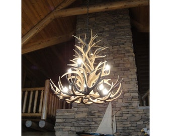May include: A large antler chandelier with multiple lights hanging from a wooden ceiling in a rustic setting.