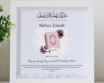 May include: A white frame with a pink and white illustration of an open Quran with prayer beads. The text in the image reads "The best of you are those who learn the Quran and teach it. Hafiza Zainab. 18th May 2024. May you always stay connected to the book of Allah. May you recite the Quran beautifully, understand it properly, act upon it consciously and teach it to others humbly. May Allah accept your efforts and reward you abundantly in both worlds. Aameen."