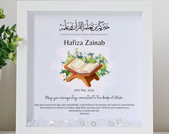 May include: A white frame with a light blue background featuring an illustration of an open Quran on a stand with flowers. The text reads "The best of you are those who learn the Quran and teach it."  "Hafiza Zainab"  "18th May 2024"  "May you always stay connected to the book of Allah"  "May you recite the Quran beautifully, understand it properly, act upon it consciously and teach it to others humbly. May Allah accept your efforts and reward you abundantly in both worlds. Aameen"