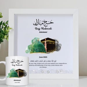 Könnte beinhalten: Ein weiß gerahmter Druck und eine passende Tasse. Der Druck und die Tasse zeigen den Text "Hajj Mubarak" auf Arabisch und Englisch, zusammen mit einer Illustration einer grünen Kuppel und der Kaaba. Der Name "Ammaar" und das Datum "Juni 2025" sind ebenfalls enthalten.