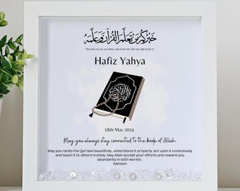 May include: A white framed print with a black and white illustration of an open book and prayer beads. The text reads "The best of you are those who learn the Qur'an and teach it."  "Hafiz Yahya"  "18th May 2024"  "May you always stay connected to the book of Allah"  "May you recite the Qur'aan beautifully, understand it properly, act upon it consciously and teach it to others humbly. May Allah accept your efforts and reward you abundantly in both worlds. Aameen"