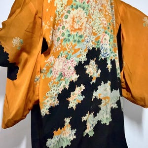 Può includere: Kimono arancione con un design floreale. La parte posteriore del kimono presenta un grande motivo floreale nelle tonalità del rosa, bianco e verde. La parte inferiore è nera con un design geometrico unico.