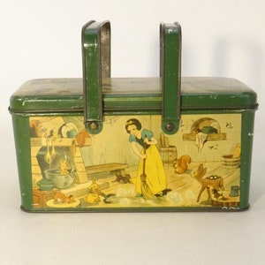 Peut inclure: Une boîte à lunch en métal vert avec une poignée. Le devant de la boîte présente une illustration vintage de Blanche-Neige nettoyant son chalet avec un balai. L'illustration comprend un cerf, des écureuils et d'autres animaux de la forêt.
