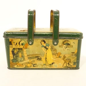 Peut inclure: Une boîte à lunch en métal vert avec une poignée. La boîte représente une scène de Blanche-Neige et les Sept Nains avec Blanche-Neige qui balaie le sol et les sept nains en arrière-plan.