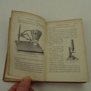May include: Two illustrations of microscopes from a vintage book on science. The first image shows a microscope with a stand and a lens. The second image shows a microscope with a stand and a lens. The text in the image reads "Microscopes en voyage" and "Microscopes d'étude".