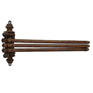 Op de afbeelding: Een donkerbruin houten handdoekenrek met drie horizontale staven die uit een decoratieve verticale steun steken. De steun heeft sierlijke details en een haak om op te hangen. Ontworpen voor wandmontage.