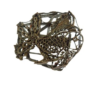 May include: A vintage, metal batik stamp in the shape of a fish. The stamp is intricately designed with a detailed pattern of scales and fins.