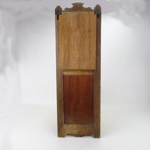 May include: A tall, wooden cabinet with a rectangular door and a smaller, rectangular door below it. The cabinet is made of dark wood with a light wood trim. The doors are closed and have a simple design.